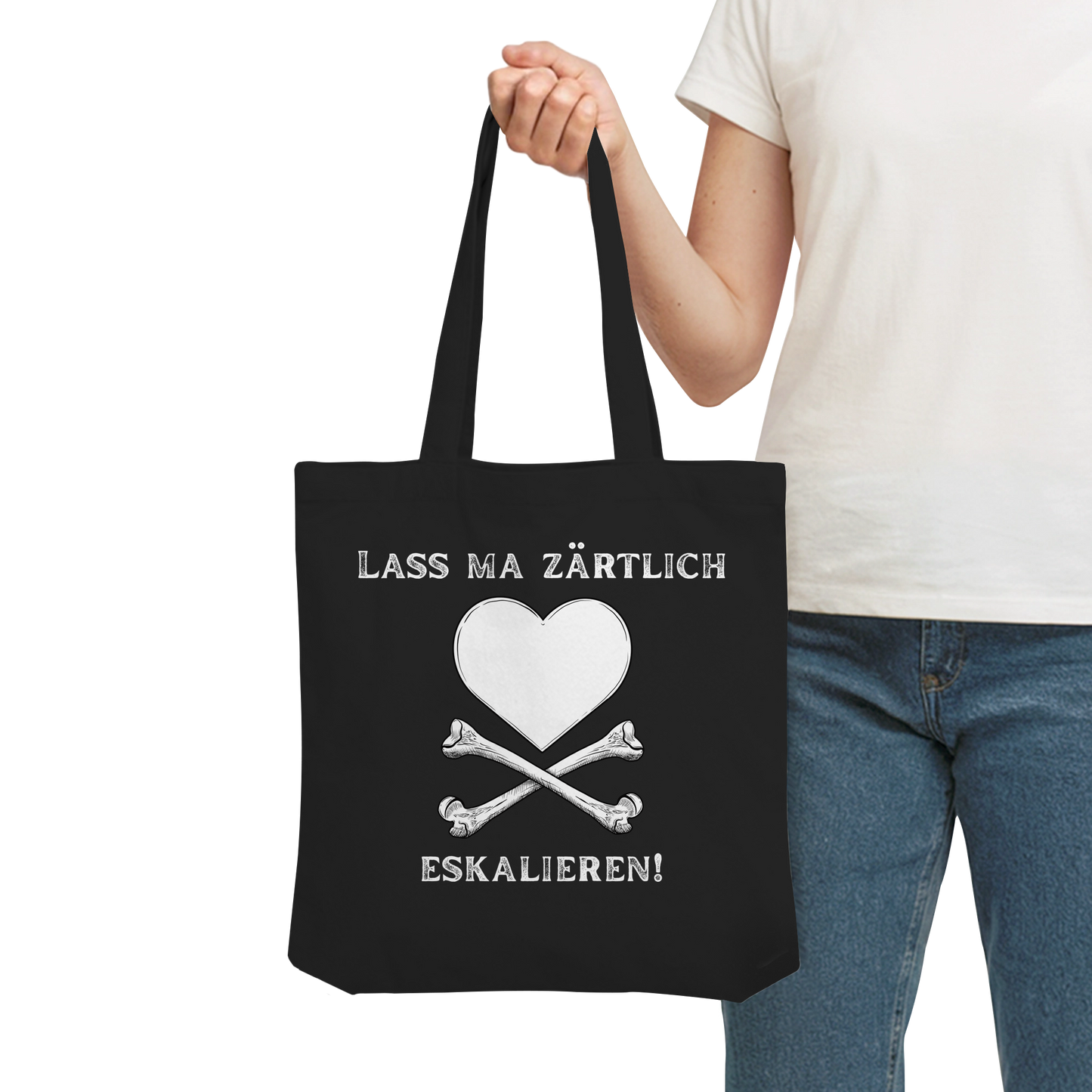 Person mit der schwarzen „Krawall + Zärtlichkeit Poetry Slam – Baumwolltragetasche – Lass ma zärtlich eskalieren“ von Artbookings/Shirtigo – weißes Herz über Knochen, perfekt für Poetry Slams.