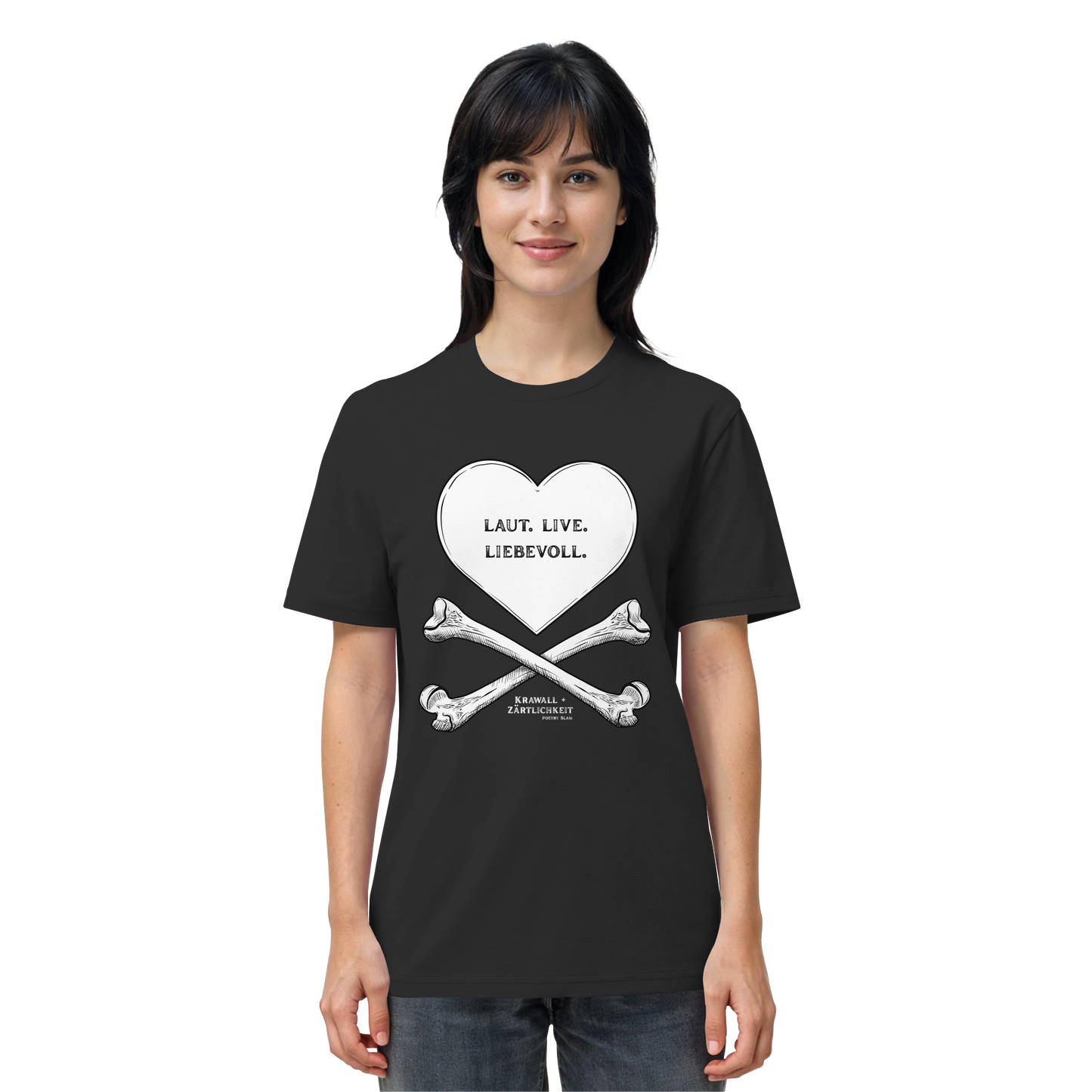 Eine Frau blickt mit einem leichten Lächeln nach vorne und trägt das Artbookings/Shirtigo-Statement-T-Shirt „Laut. Live. Liebevoll.“ (Weiß auf Schwarz). Das schwarze Shirt zeigt eine auffällige Grafik aus einem Herz und gekreuzten Knochen mit der Aufschrift „LAUT. LIEB. LIEBEVOLL.“ auf Deutsch – ein Motiv, das den Geist von „Krawall + Zärtlichkeit“ verkörpert, der bei Veranstaltungen wie dem Poetry Slam Essen beliebt ist.
