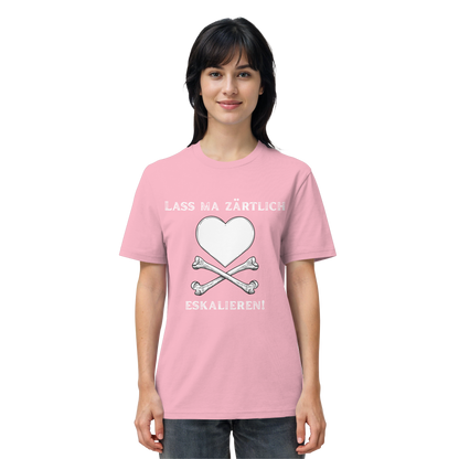 Eine Frau trägt das T-Shirt „Lass ma zärtlich eskalieren!“ von Artbookings/Shirtigo zum Poetry Slam „Krawall + Zärtlichkeit“ in Bio-Qualität, das mit einem rosa Motiv mit Herz, gekreuzten Knochen und einem deutschen Slogan bedruckt ist.