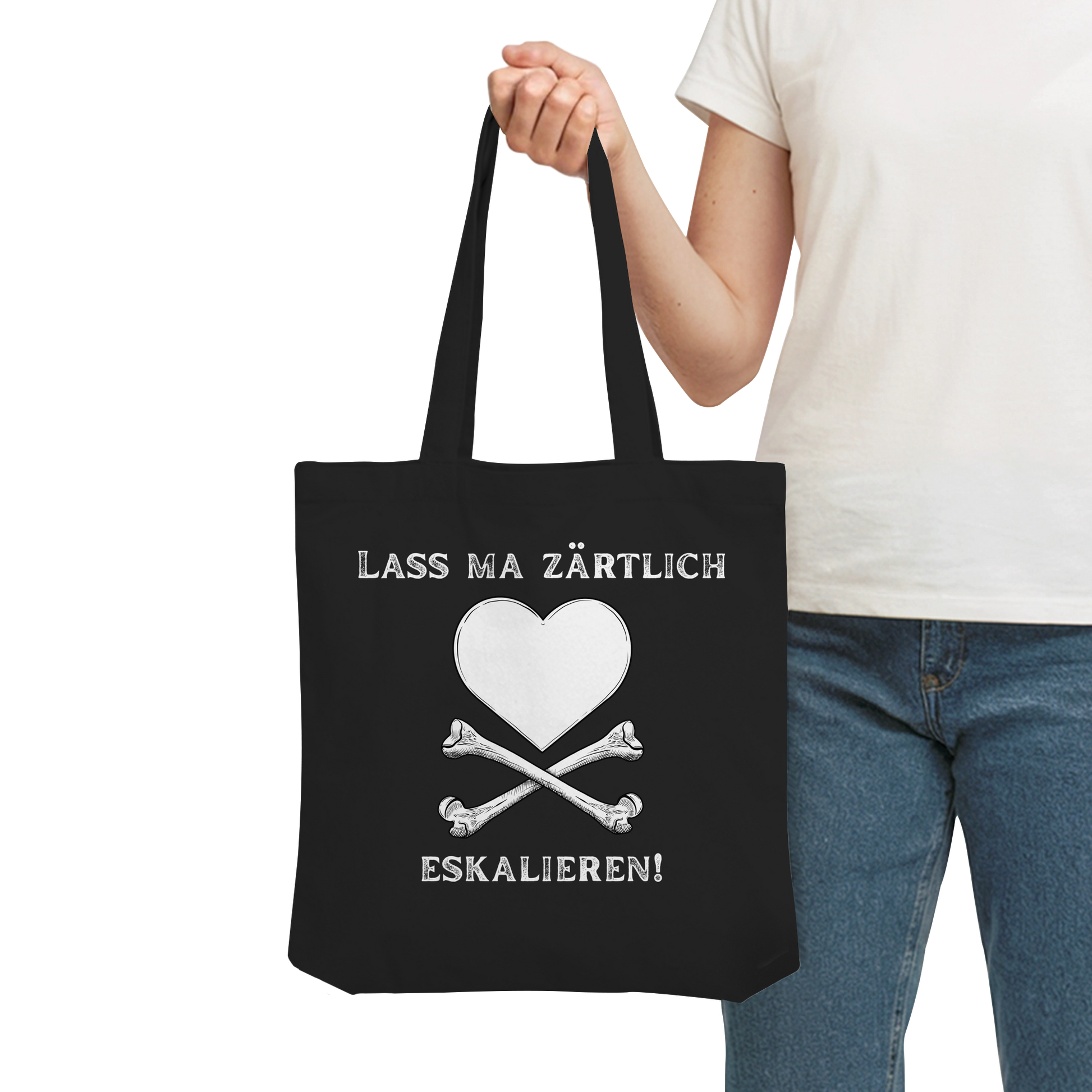 Person mit der schwarzen „Krawall + Zärtlichkeit Poetry Slam – Baumwolltragetasche – Lass ma zärtlich eskalieren“ von Artbookings/Shirtigo – weißes Herz über Knochen, perfekt für Poetry Slams.